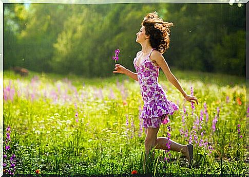 Mujer-caminando-entre-flores-sonriendo-y-feliz